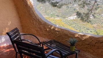 A bench and table inside a room with a view of a mountainous landscape.