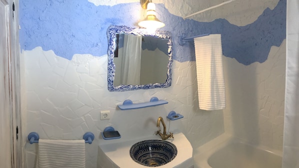 Un baño con un lavamanos blanco, un espejo con marco azul y un perchero para toallas.