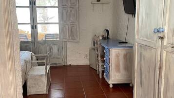 Une pièce rustique avec un meuble en bois, une petite table avec des tiroirs, une chaise et un téléviseur fixé au mur.
