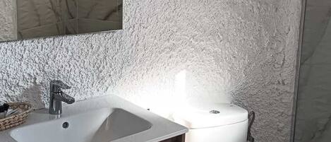 A bathroom with a white sink, wooden cabinet, and a toilet.