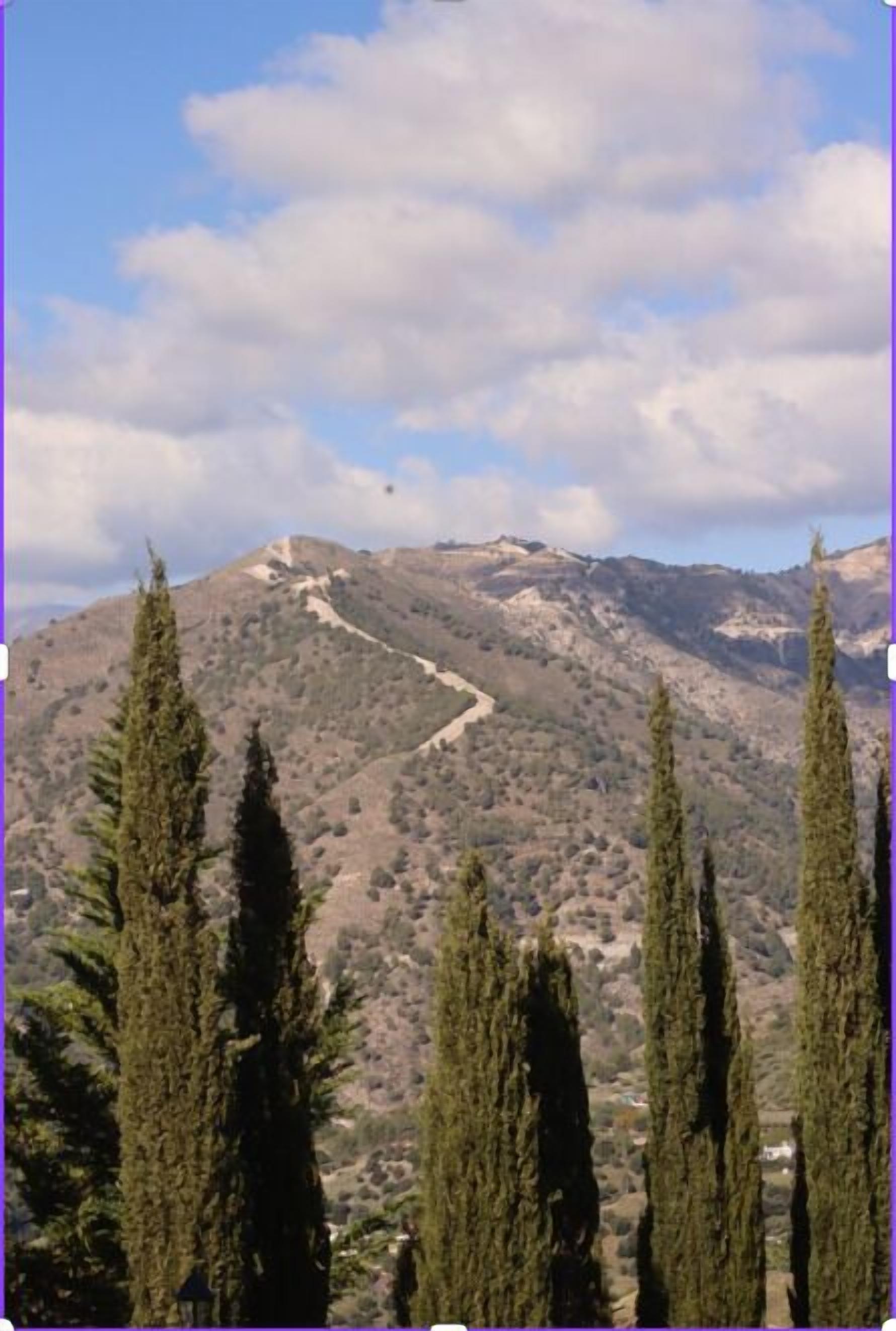Un paysage montagneux, avec un ciel dégagé et un sentier sinueux.