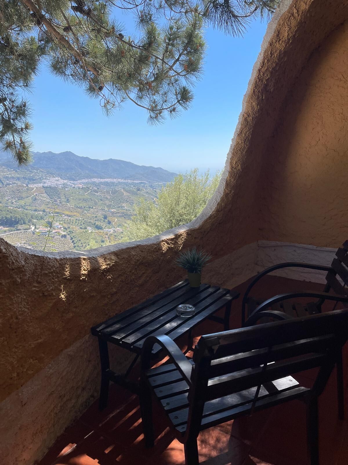 Un espacio de estar al aire libre rústico con vistas a un valle y montañas.