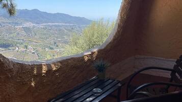 Un espacio de estar al aire libre rústico con vistas a un valle y montañas.