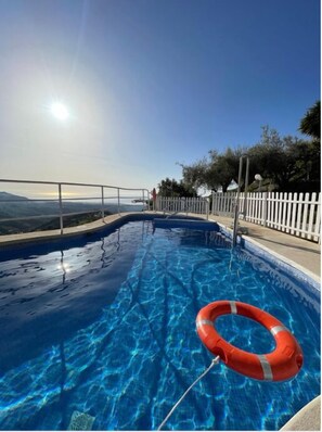 A swimming pool with a clear view of the surrounding landscape and a white fence.