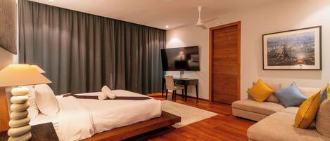 Una habitación de hotel moderna con cama, sofá, escritorio y televisor.