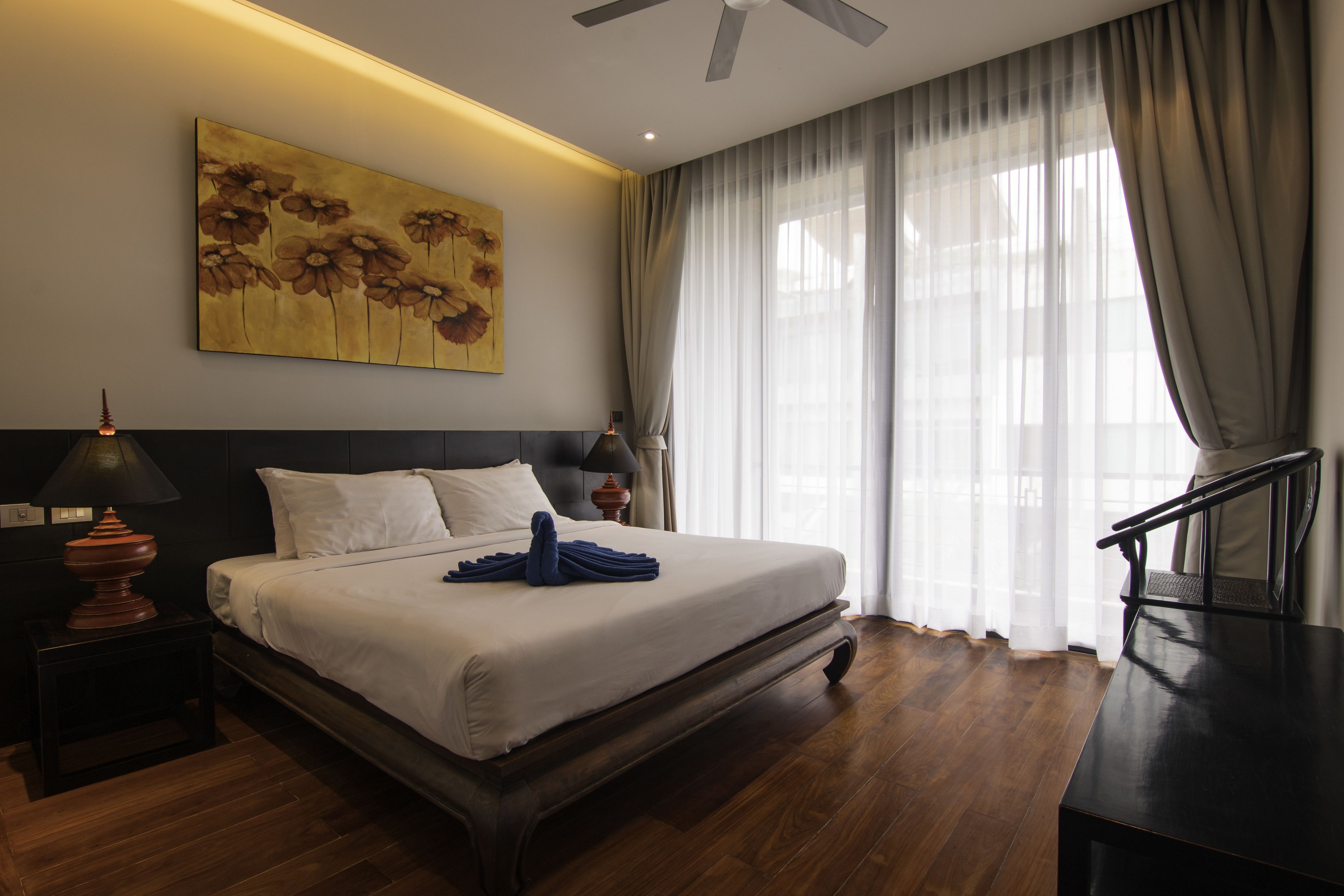 Ein Hotelzimmer mit einem großen Bett, einem Schreibtisch, einem Deckenventilator und einem Bild an der Wand.
