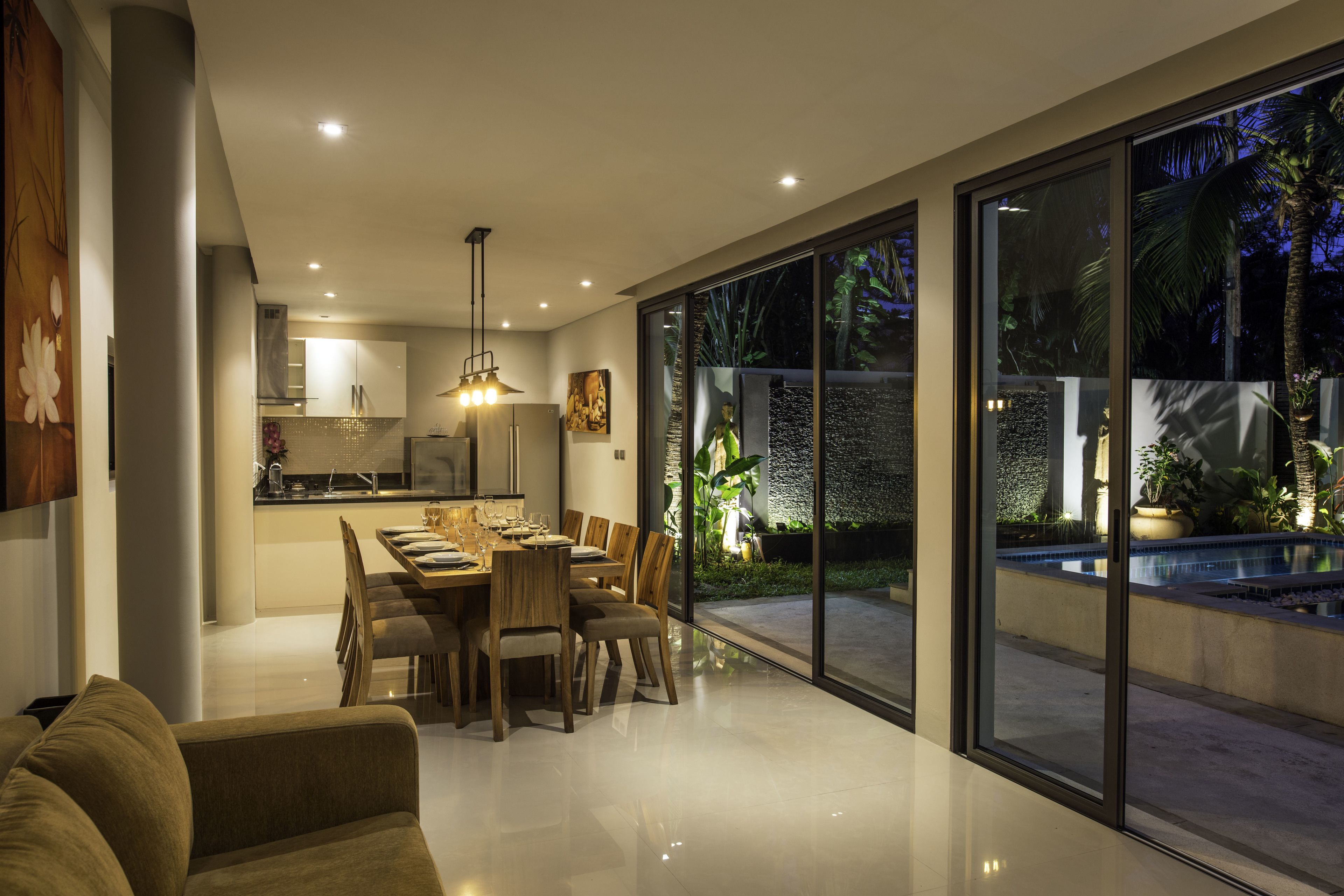 A modern kitchen with a dining area, large windows, and a pool.