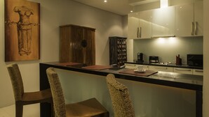 A modern kitchen with a bar area, wooden chairs, and a large cabinet. - Amazing 5BR Seaview Private Pool Villa by Intira Villas (Rawai)