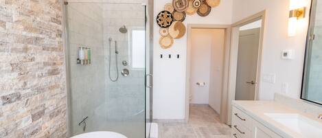 Un baño moderno con ducha envuelta en vidrio, bañera blanca y un espejo grande.