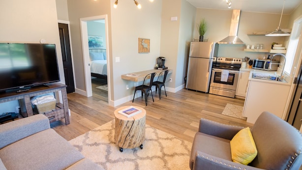 A modern living room with a flat-screen TV, a wooden coffee table, and a grey sofa.