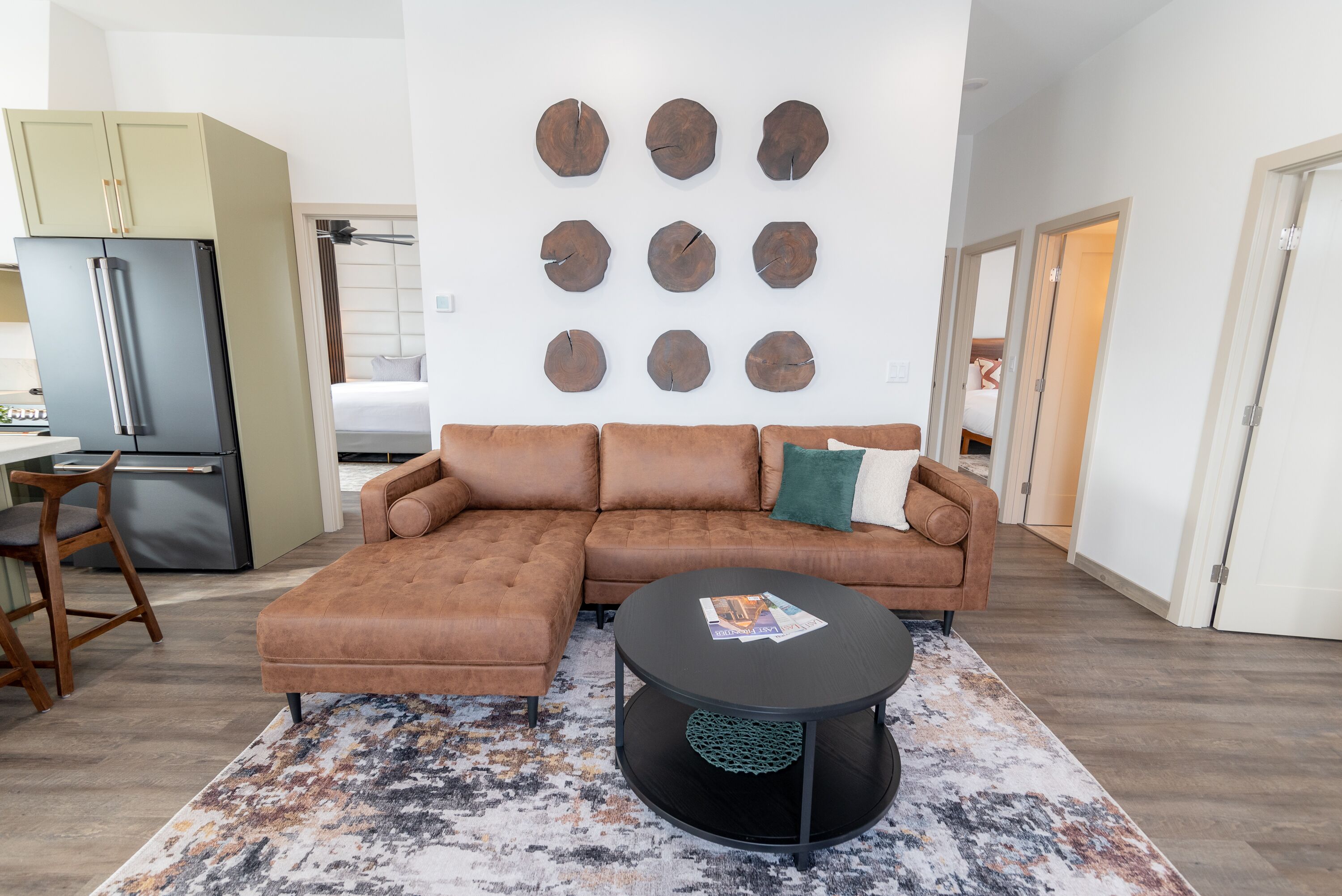 Un salon moderne avec un canapé d’angle, une table basse ronde et une horloge murale.