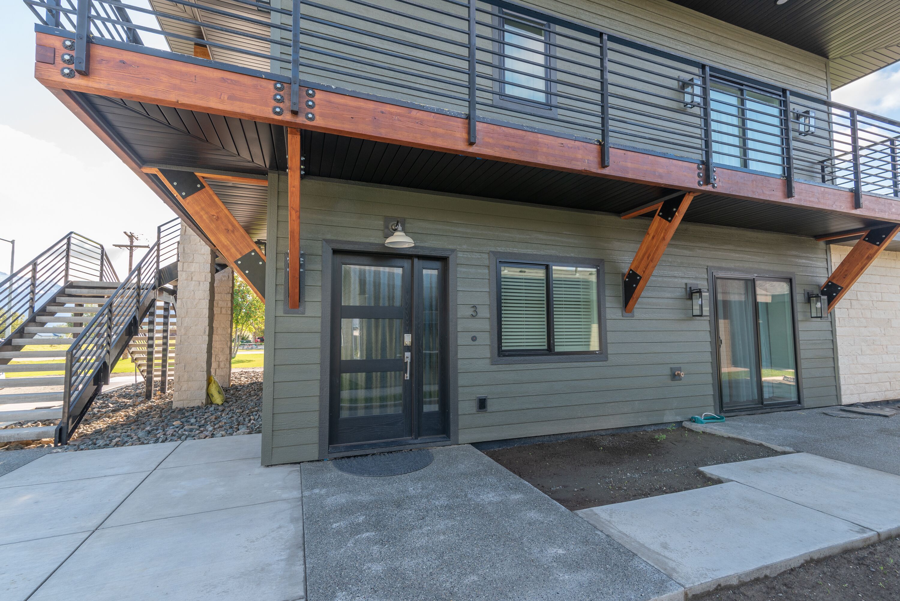 A two-story building with a balcony, a front door, and a staircase leading to an upper level.