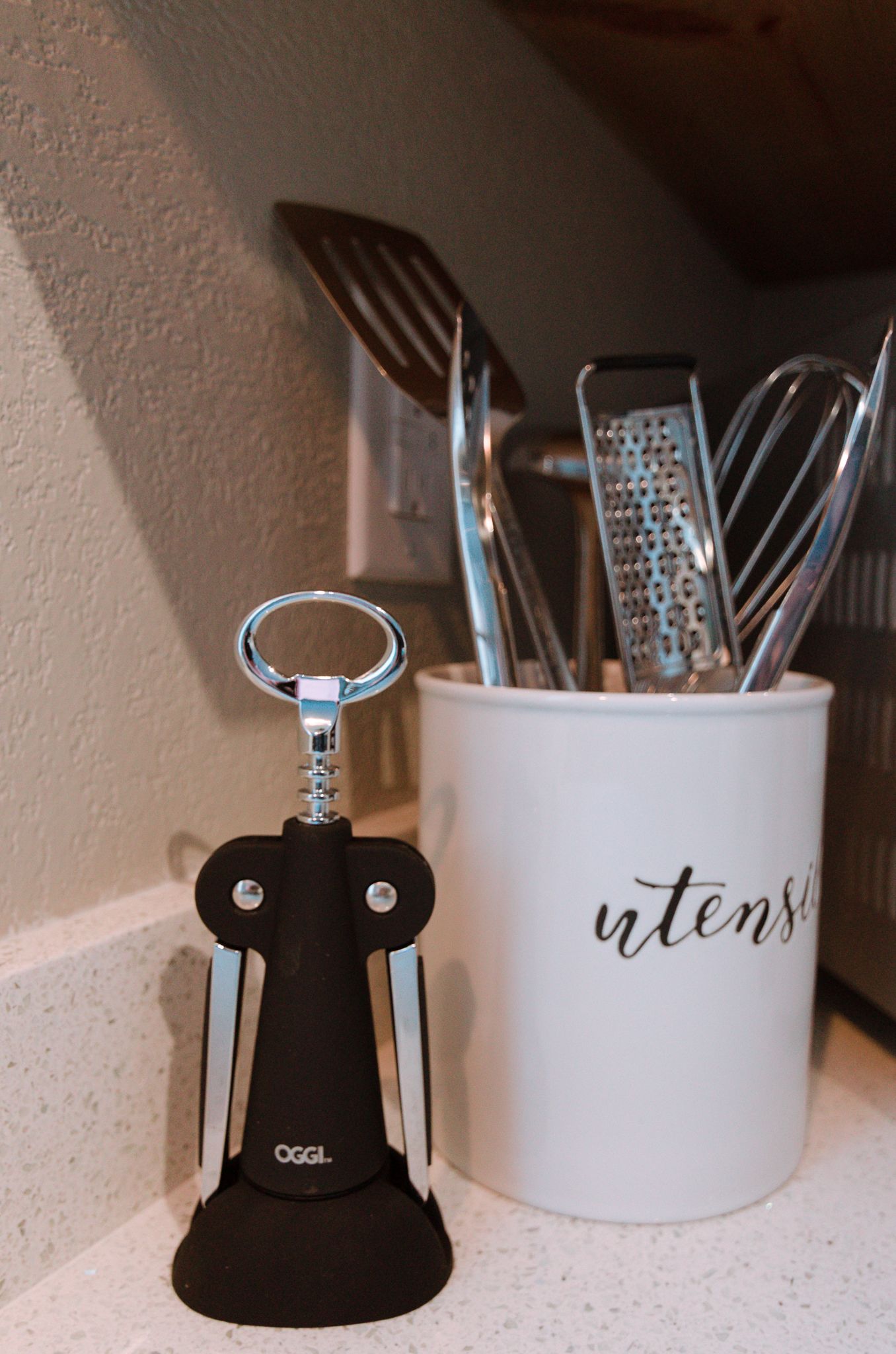 A corkscrew and a mug with utensils.