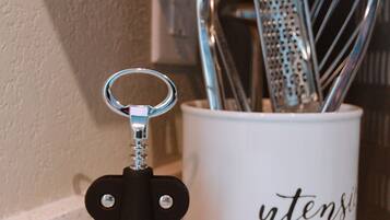 A corkscrew and a mug with utensils.