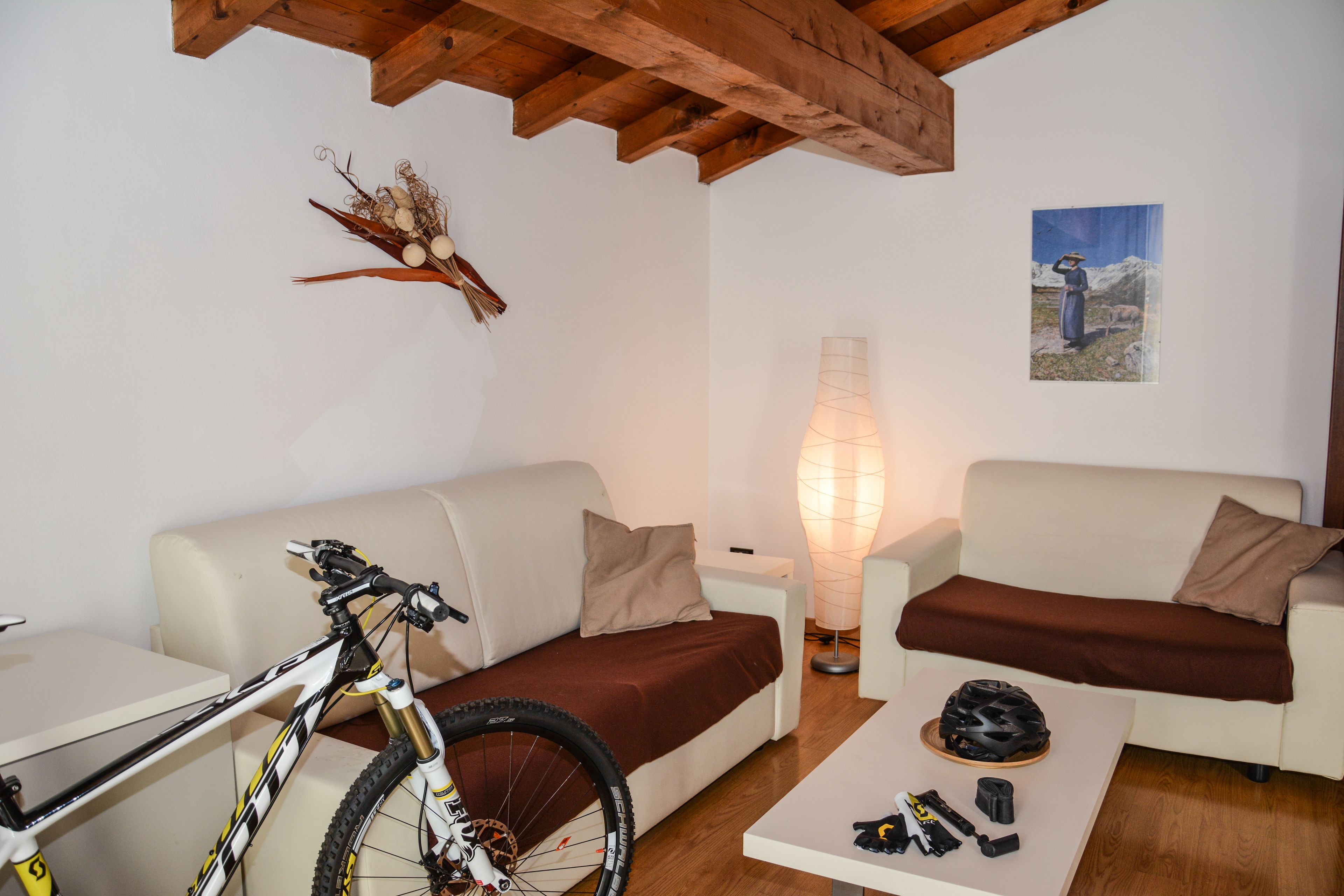 A living room with a bicycle, two couches, a table with a helmet, and a lamp.
