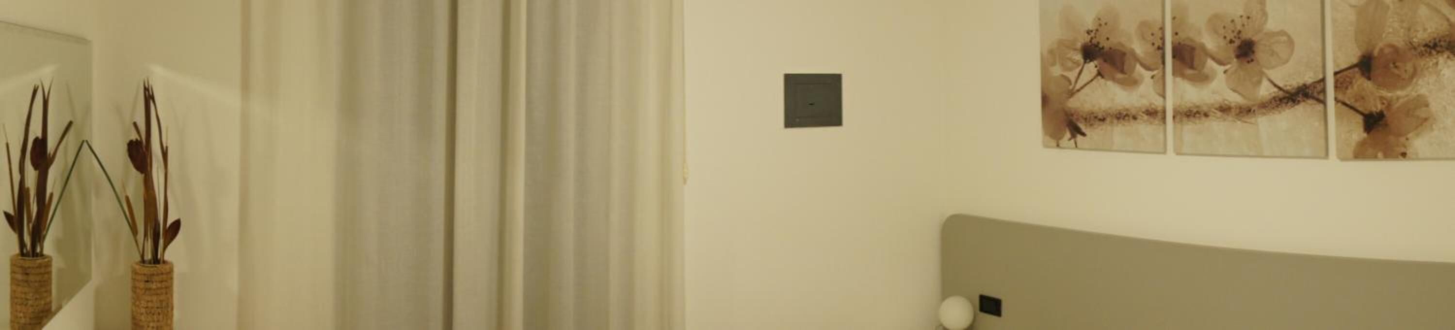 Una stanza con un letto, una lampada a parete e un quadro.