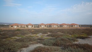 A row of stone buildings with red roofs, likely a dormitory or hostel, in a dry, open landscape. - Bungalows Bela Vista Maio Beach (Maio)