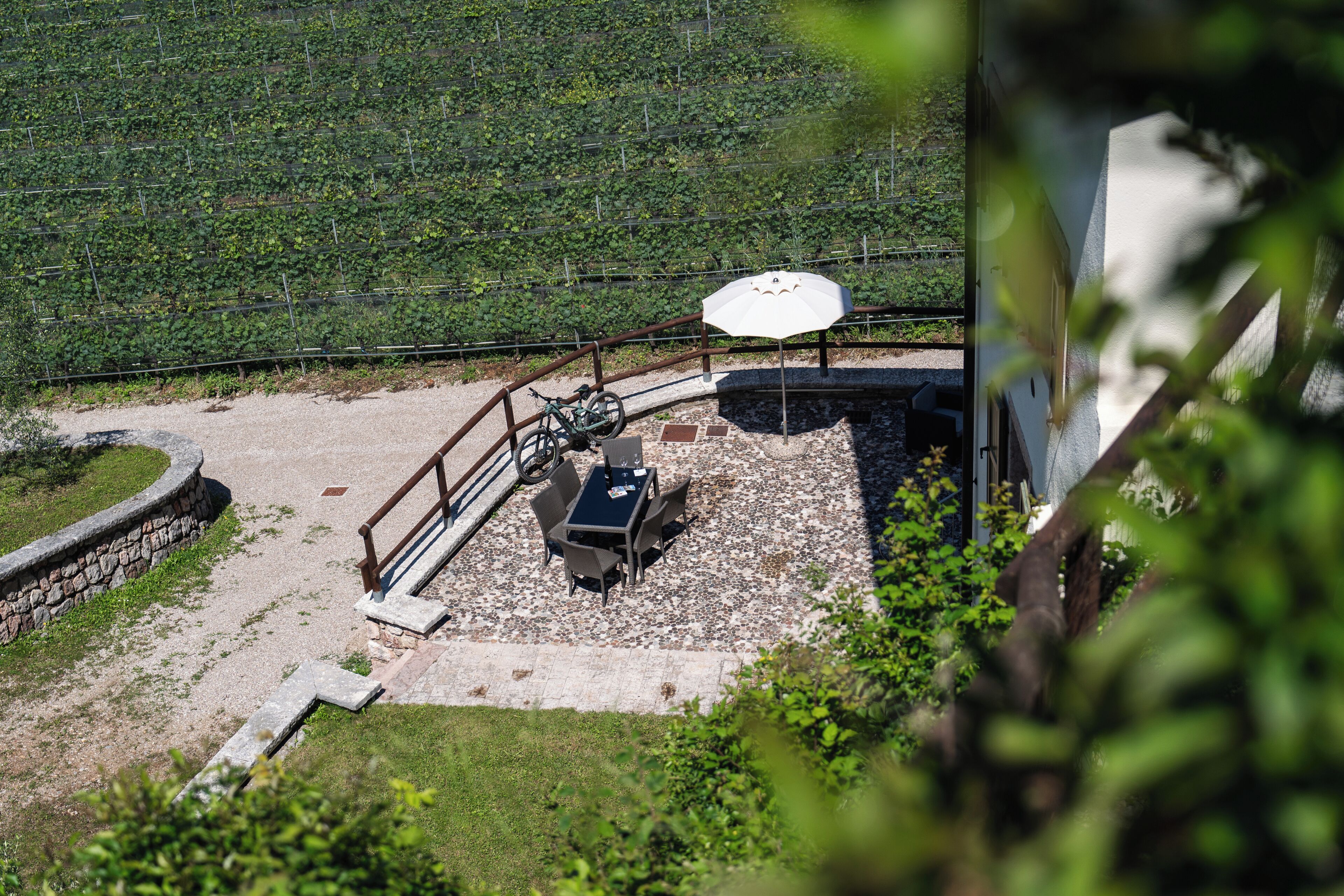 A patio area with a table and chairs, a bicycle, and a white umbrella.