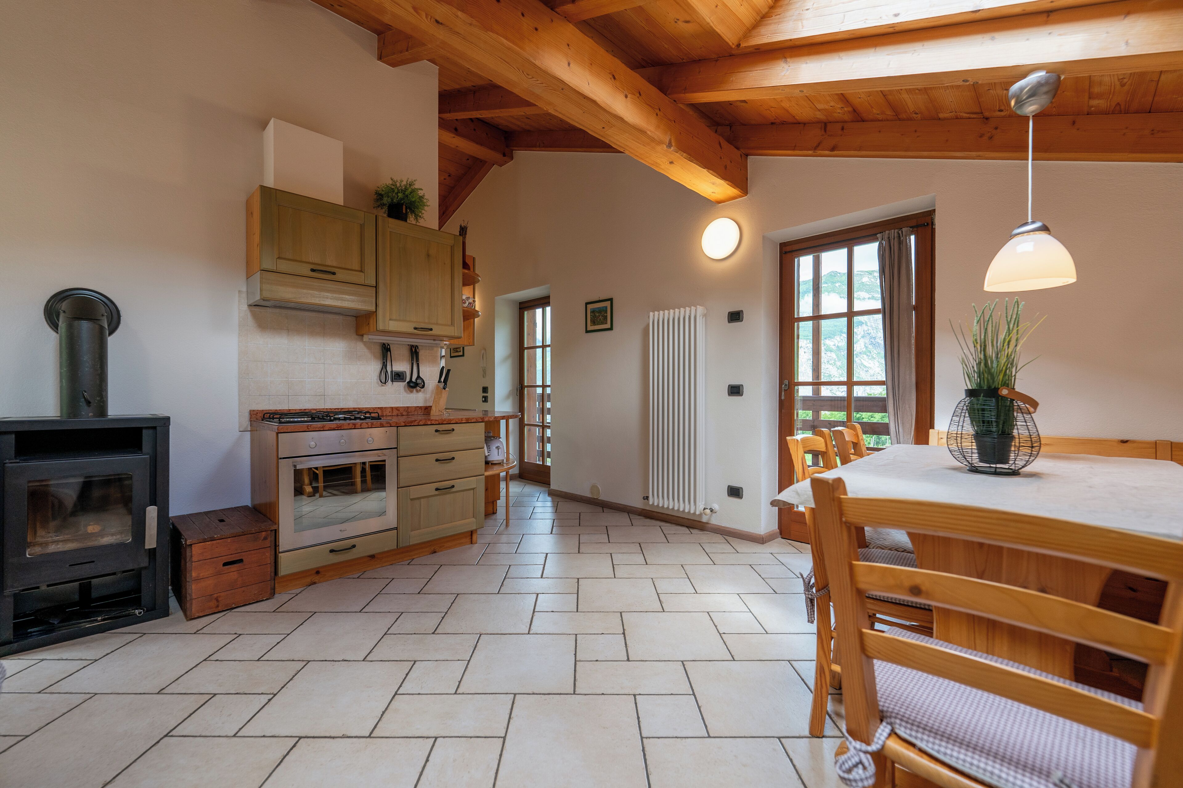A kitchen with wooden cabinets, a stove, and a dining area with a table and chairs.