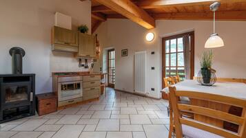 A kitchen with wooden cabinets, a stove, and a dining area with a table and chairs.
