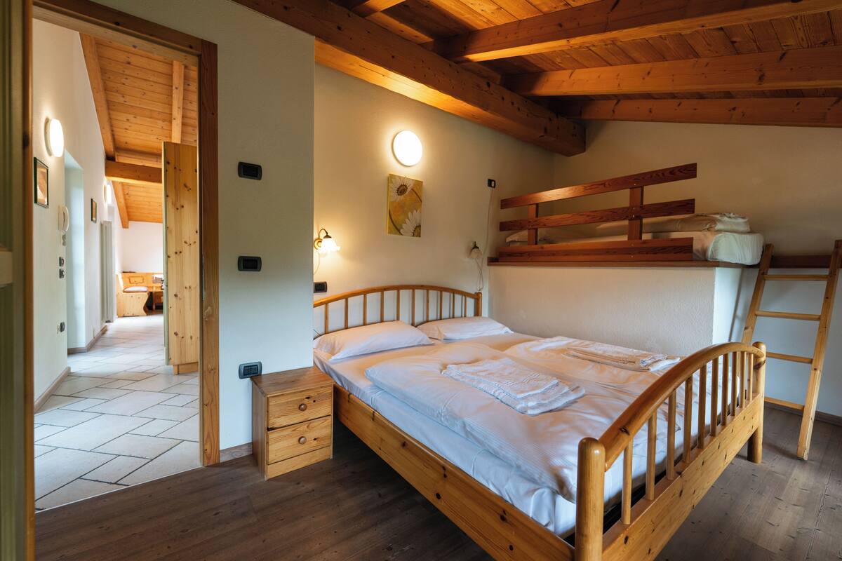 Uma cama de madeira com cabeceira, mesa de cabeceira e luminária na parede.