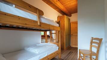 A bunk bed room with a wooden chair and a door.