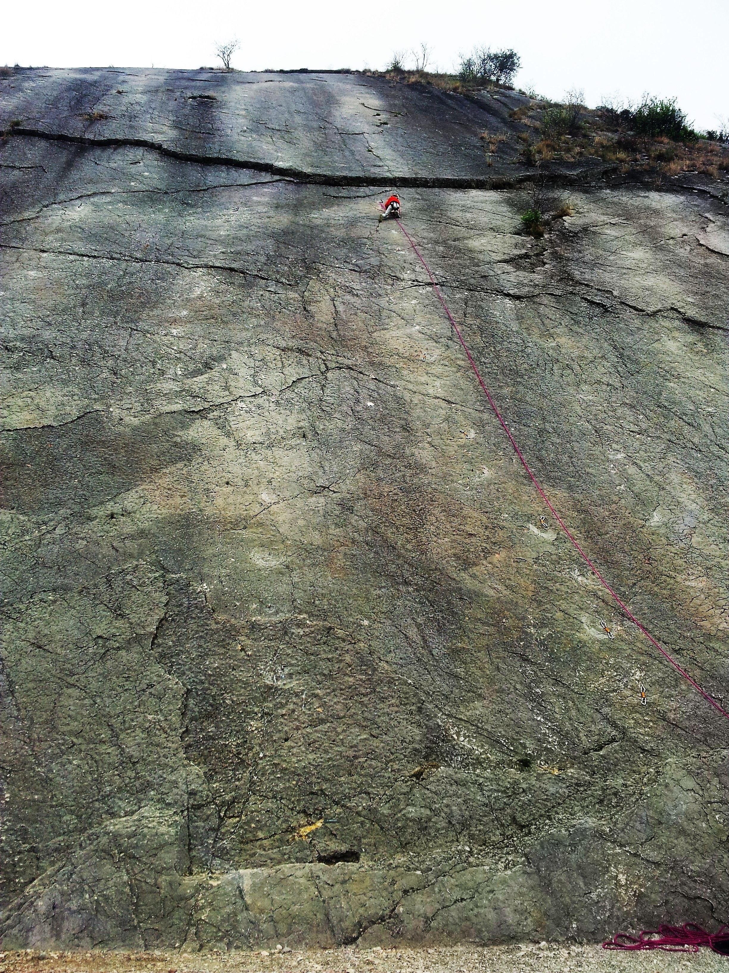 A large rock face with visible cracks and a red rope.