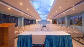Un salón de conferencias con techo alto, tragaluz y una larga mesa con sillas.