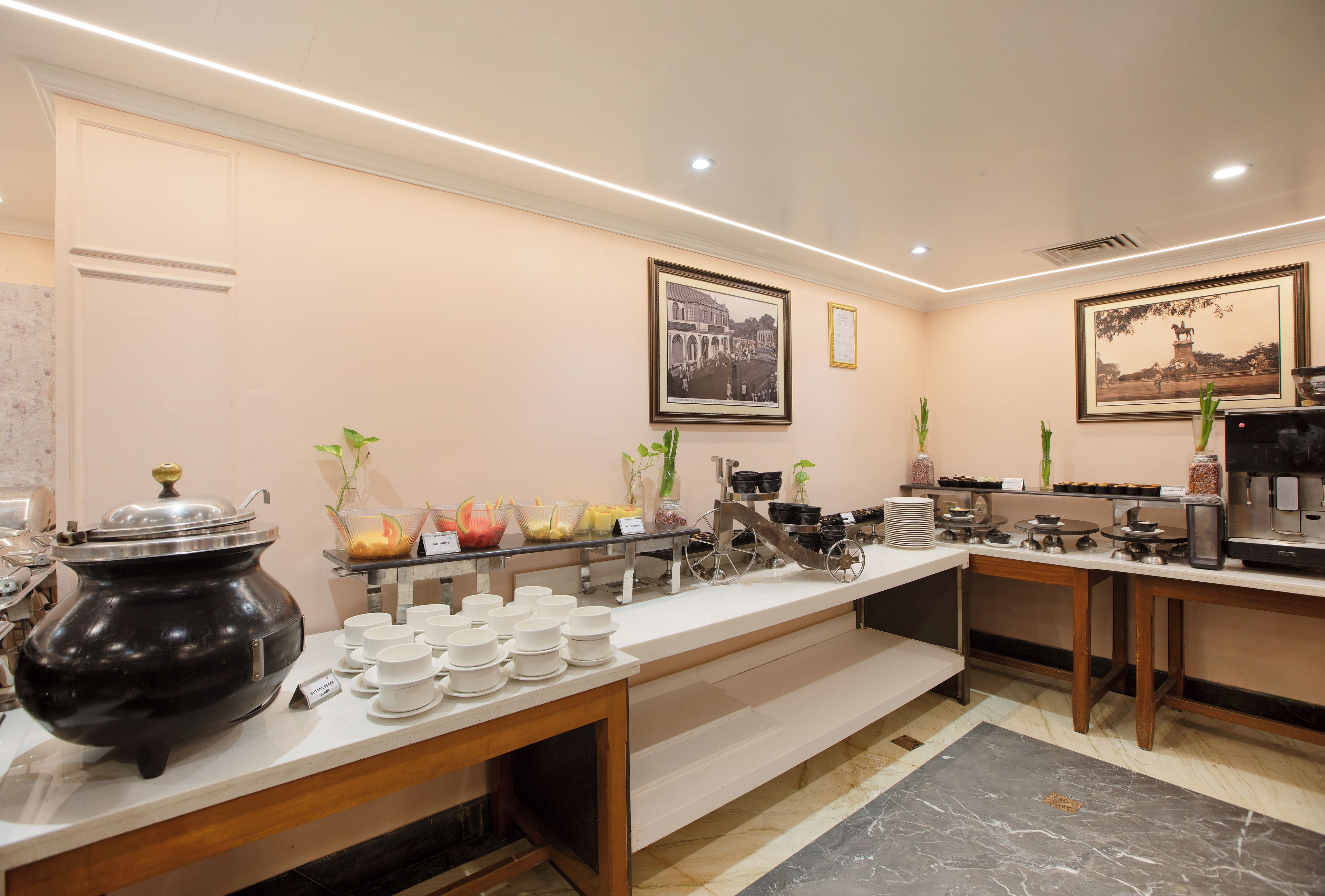 Habitación de hotel con desayunador, una tetera negra grande y piso de mármol.