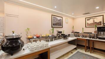 Habitación de hotel con desayunador, una tetera negra grande y piso de mármol.