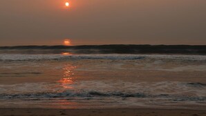 Atardecer sobre el océano con olas reflejando la luz del sol.