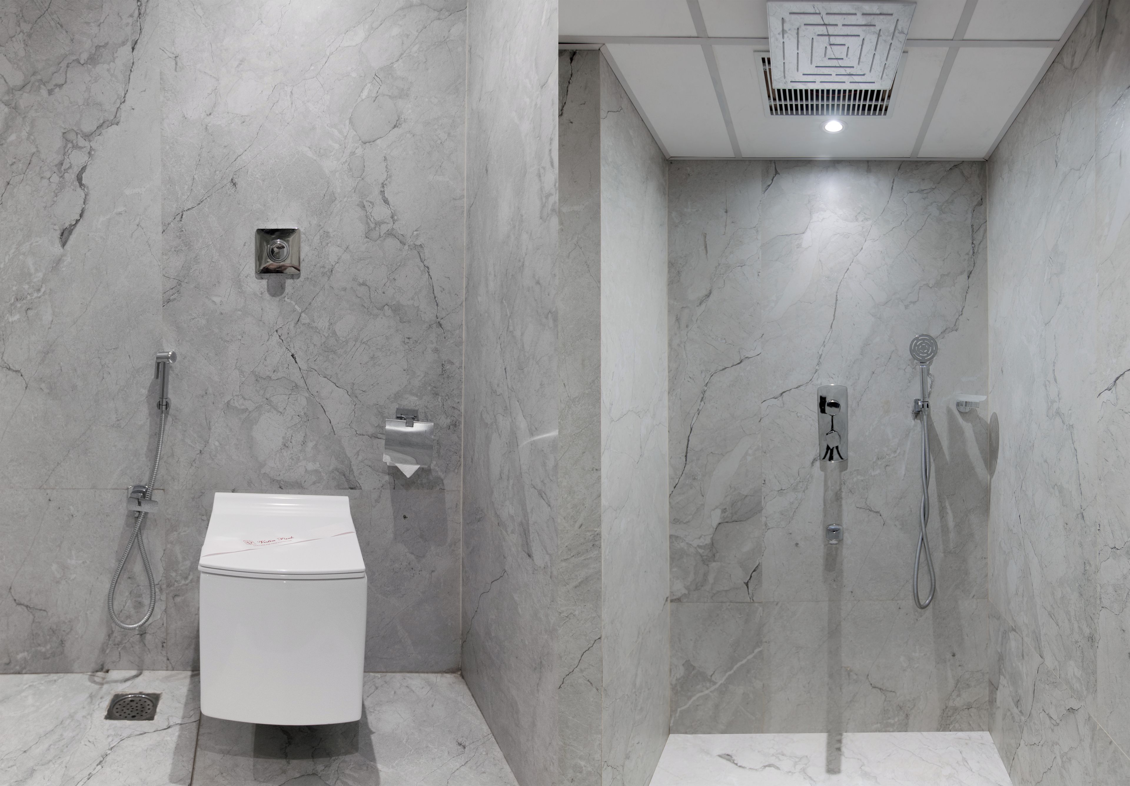 A modern bathroom with a toilet, shower, and marble walls.