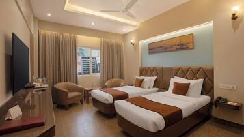 A hotel room with two beds, a desk, a chair, a TV, and a window with curtains.