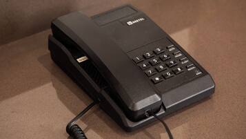 A black telephone with a cord, placed on a brown surface.