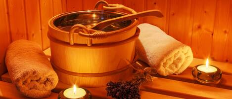 Una sauna de madera con una bañera grande de madera, dos toallas enrolladas y dos velas encendidas.