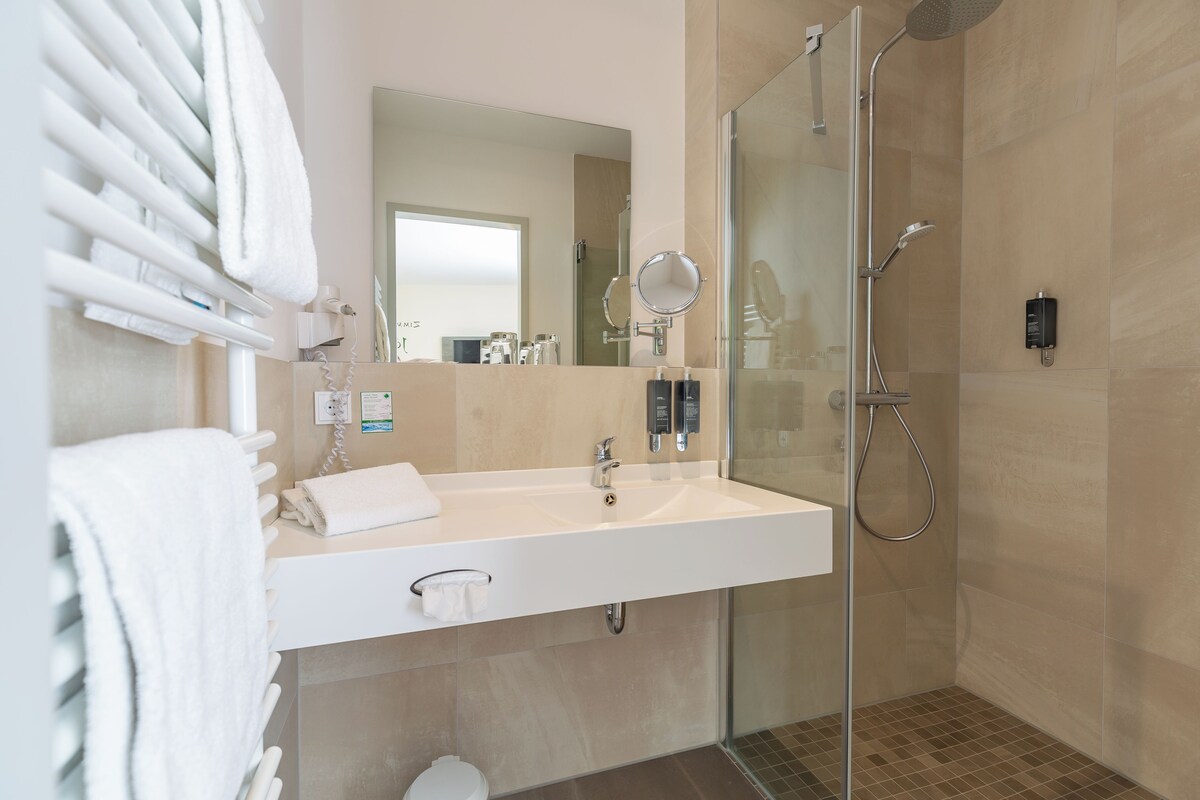 Un baño moderno con cabina de ducha de vidrio, un lavabo blanco y un espejo.