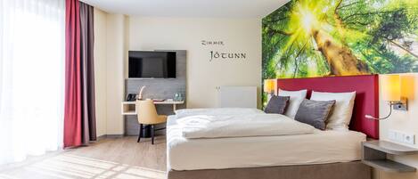 A modern hotel room with a large bed, a desk, and a TV.