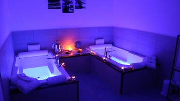 Bathroom features two sinks and a bathtub, with towels and a table with a candle.