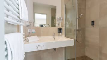 Un baño moderno con cabina de ducha de vidrio, un lavabo blanco y un espejo.