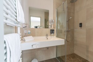 Un baño moderno con cabina de ducha de vidrio, un lavabo blanco y un espejo.