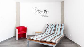 Un dormitorio con una cama, una silla roja y una mesita.