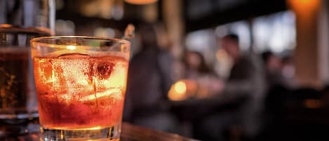 Une ambiance de bar avec un verre contenant une boisson ambrée, des glaçons et une tranche de citron vert.