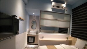 A modern bedroom with a bed, a vanity with a mirror, a built-in shelf, and a window with blinds. - itravel Hostel (Hualien City)
