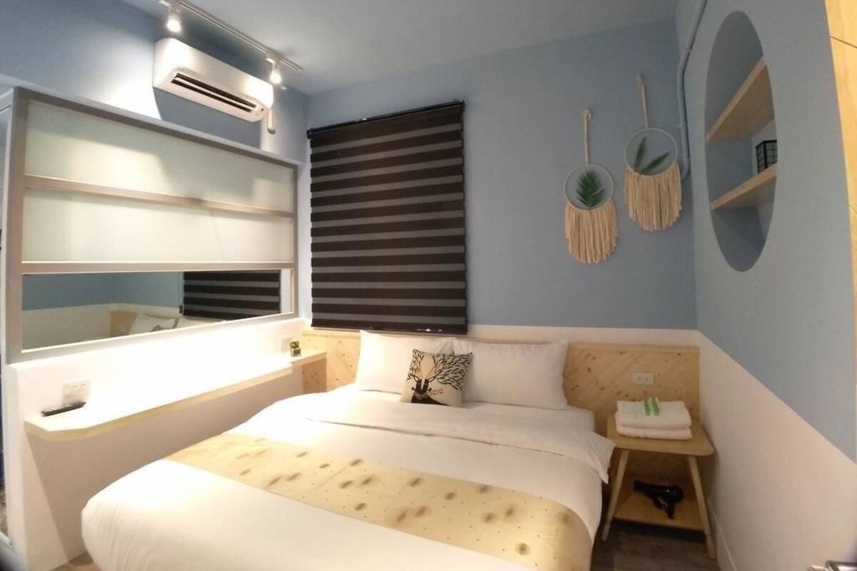 A bedroom with a bed, bedside table, and wall-mounted air conditioning unit.