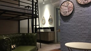 A modern interior with a green leather sofa, a round table, a kitchen area, and decorative wall art. - itravel Hostel (Hualien City)