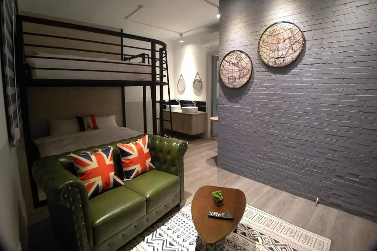 A compact room with a bunk bed, a green leather sofa with a Union Jack pillow, a small wooden coffee table, and two wall-mounted decorative plates.
