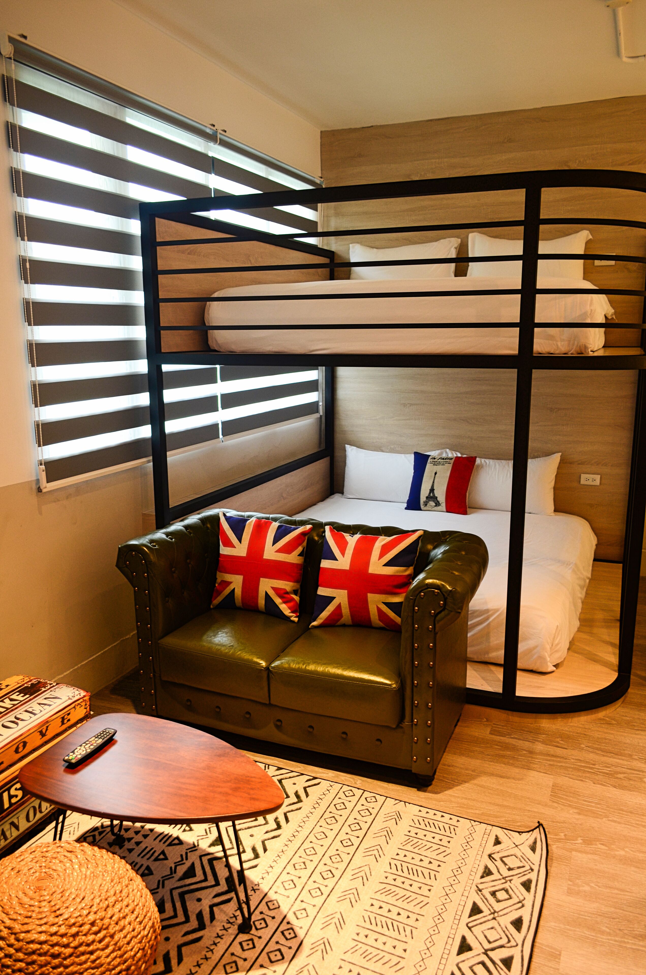 A bunk bed room with a leather sofa, a small table, and a patterned rug.