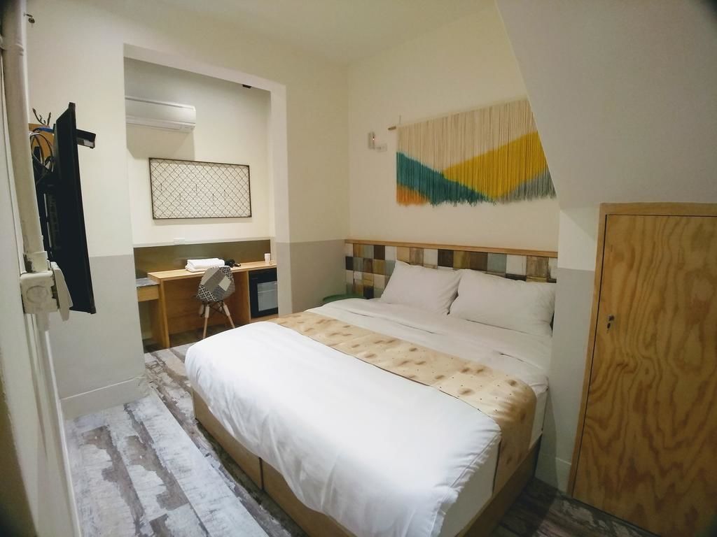 A bedroom with a bed, a desk, and a wardrobe.