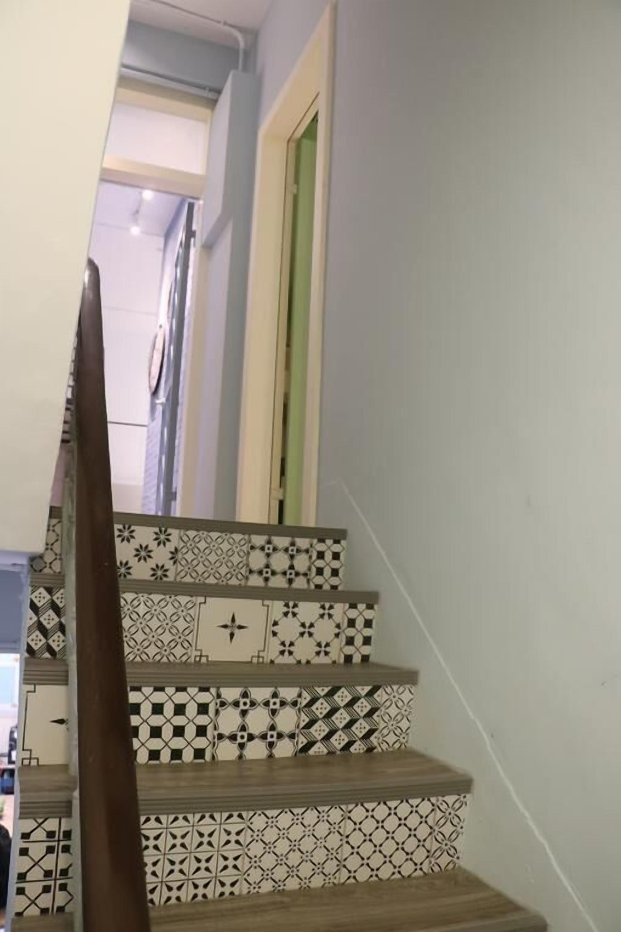A staircase with patterned tiles and a wooden handrail.