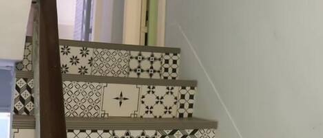 A staircase with patterned tiles and a wooden handrail.